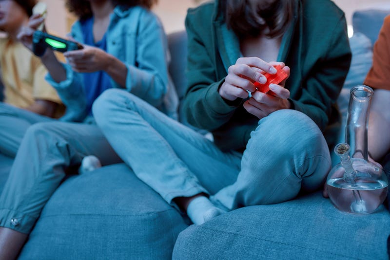 girl sitting on a couch with a bong and a weed grinder