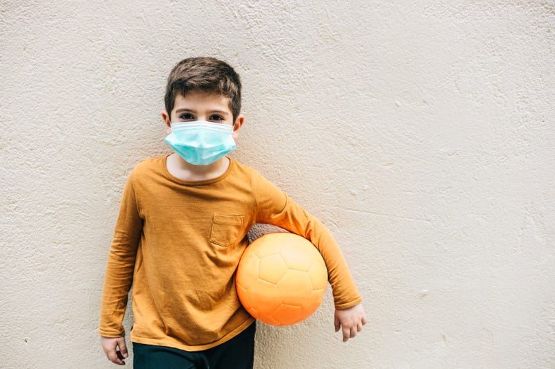 Little boy with a ball and protective mask