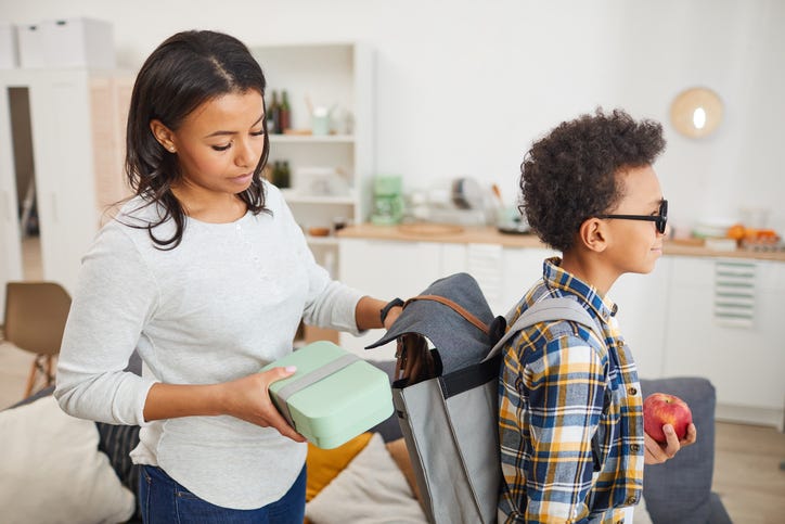mother packs son's backpack for school