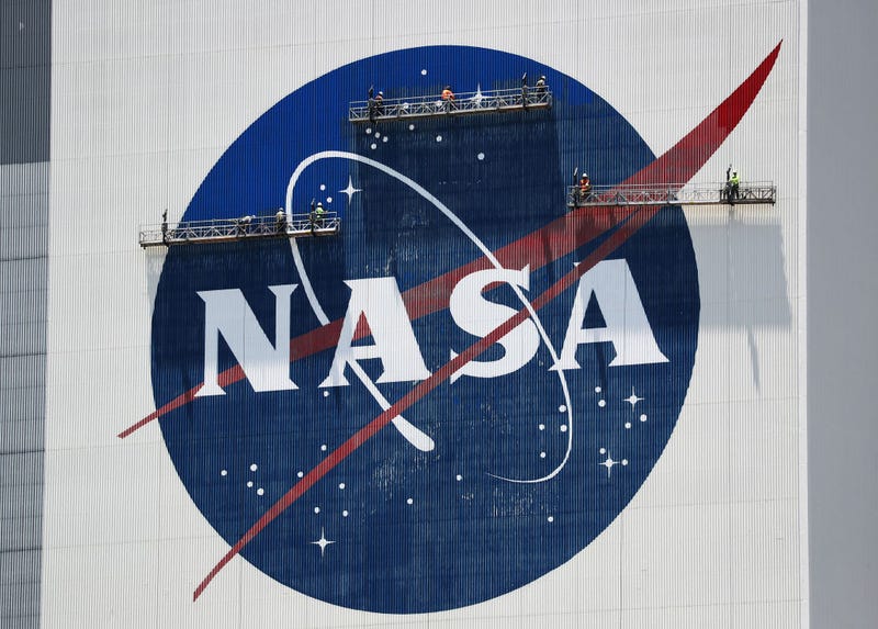 Workers freshen up the paint on the NASA logo on the Vehicle Assembly Building before the arrival of NASA astronauts Bob Behnken and Doug Hurley at the Kennedy Space Center on May 20, 2020 in Cape Canaveral, Florida.