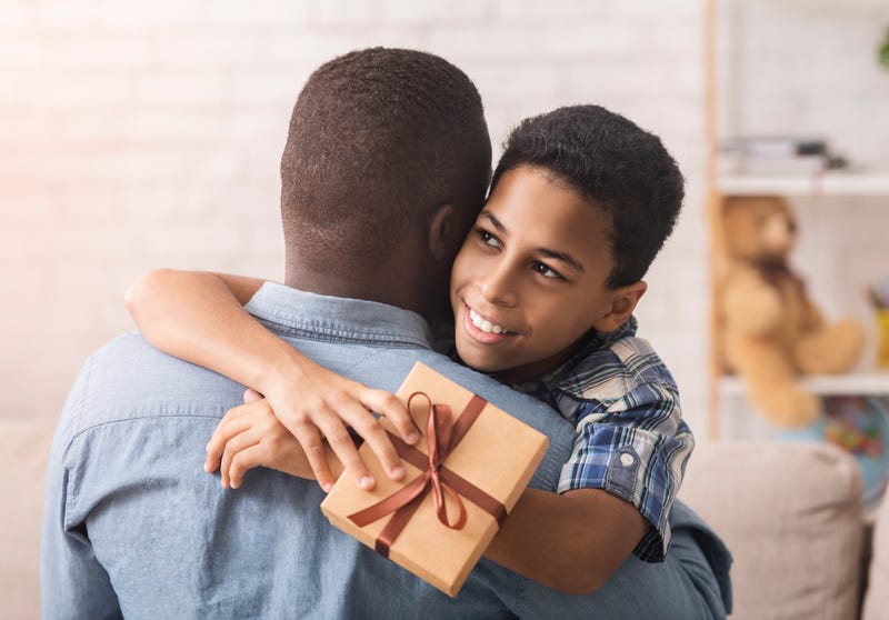 A boy hugs his Dad while giving him a gift of Fathers' Day