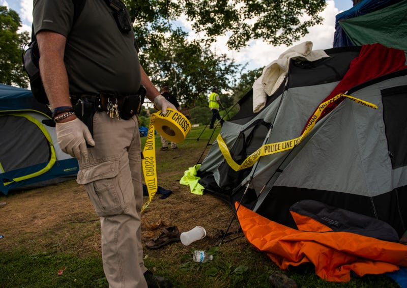A member of the Minneapolis Police Department marks a tent for removal at an encampment in Powderhorn Park in Minneapolis, Minnesota.  