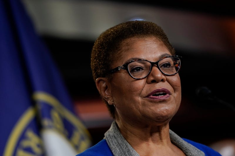 karen bass speaks in front of flag