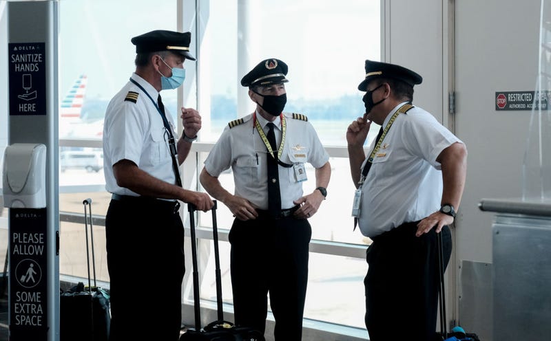 Pilots talk after exiting a Delta Airlines flight at the Ronald Reagan National Airport on July 22, 2020 in Arlington, Virginia. During the COVID-19 pandemic, all employees and passengers are required to wear facemasks while onboard a Delta plane. (Photo by Michael A. McCoy/Getty Images)