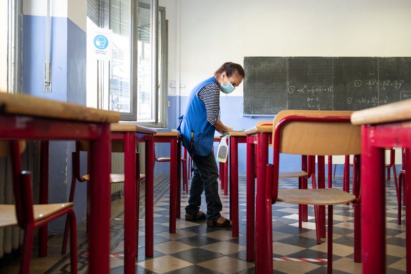 A school worker disinfects the desks at the end of the first day of school on September 15, 2020 in Turin, Italy.