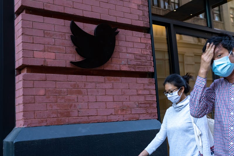 People wearing face masks walk past a Twitter logo outside their New York City headquarters. Facebook and Twitter took steps to limit the spread of a controversial New York Post article critical of Joe Biden, sparking outrage among conservatives and stoking debate over how social media platforms should tackle misinformation ahead of the US election. 