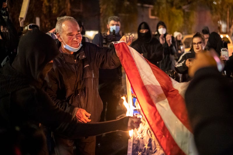 VANCOUVER, WA - OCTOBER 31: Protesters burn an American flag taken from the Washington State Patrol Forensics Building on October 31, 2020 in Vancouver, Washington. Dueling protests continued Saturday night after police shot and killed Kevin E. Peterson Jr., on Thursday night. (Photo by Nathan Howard/Getty Images)