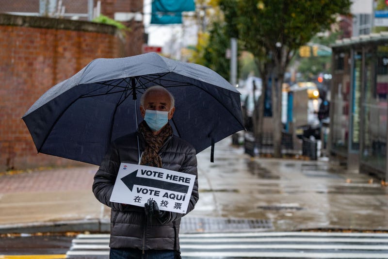 A poll worker hold a sign directing voters in the rain