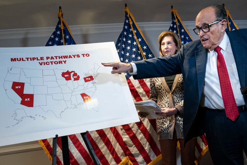 Rudy Giuliani points to a map as he speaks to the press about various lawsuits related to the 2020 election, inside the Republican National Committee headquarters on November 19, 2020 in Washington, DC. President Donald Trump, who has not been seen publicly in several days, continues to push baseless claims about election fraud and dispute the results of the 2020 United States presidential election. Also pictured, at center, is attorney Sidney Powell. (Photo by Drew Angerer/Getty Images)