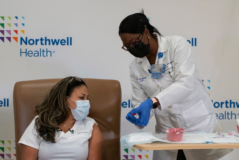 Michelle Chester (R), DNP, director, employee health services, Northwell shows the Moderna coronavirus disease (COVID-19) vaccine to Arlene Ramirez, RN, director, patient care, ED, Long Island Jewish Valley Stream, at Northwell Health's Long Island Jewish Valley Stream hospital in New York City, December 21, 2020. 