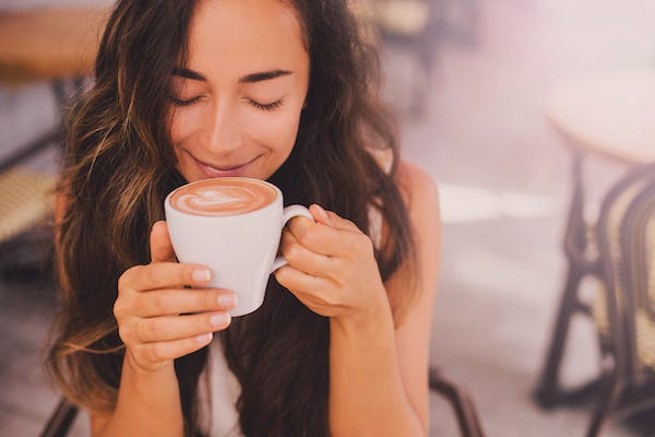 Woman smelling cappuccino in cafe
