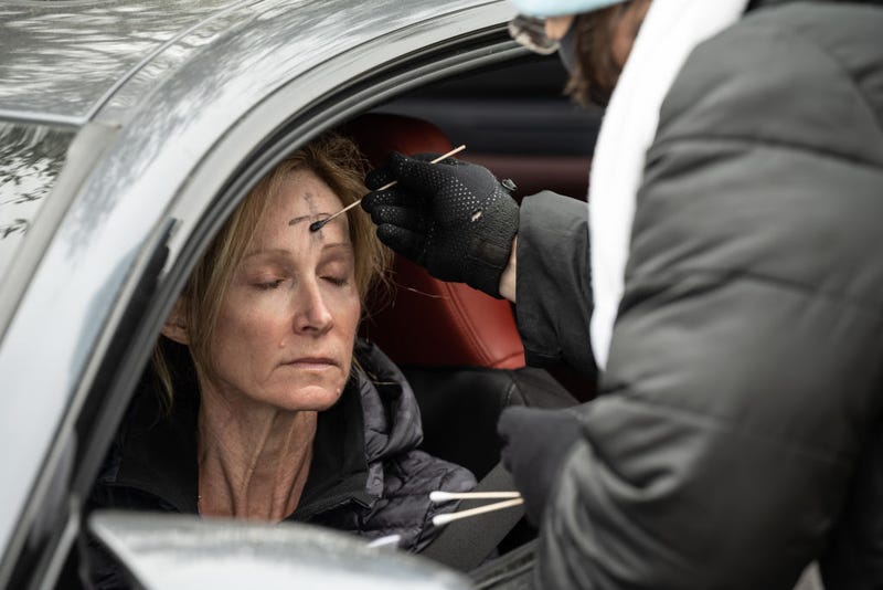A clergy member from Munholland United Methodist Church spreads ashes on the forehead of a congregant in the drive-thru Ash Wednesday prayer