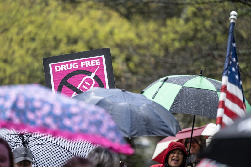 An anti-vaccination sign is seen above a row of umbrellas while demonstrators chant with speakers during a protest on state capitol grounds on April 14, 2021 in Frankfort, Kentucky. (Photo by Jon Cherry/Getty Images)