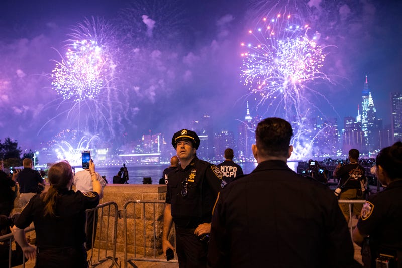 NYPD officers watch fireworks lighting up the night sky over the East River as seen from Hunter's Park South on July 4, 2021, in Queens