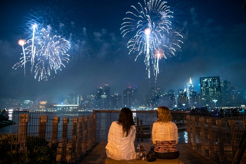 People watch fireworks lighting up the night sky over the East River from Hunter's Park South on July 04, 2021 in the Queens borough of New York City. This is the 45th annual display of the Macy's Independence Day fireworks show.