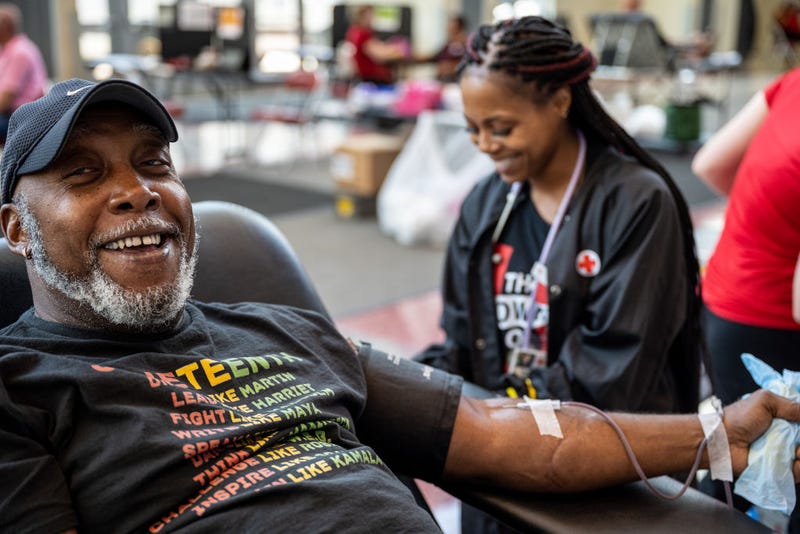 A man laughs with the phlebotomist assigned to him while donating blood.