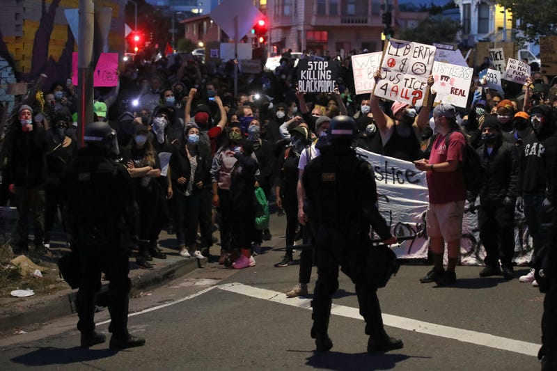Demonstrators hold signs in front of California Highway Patrol officers during a protest sparked by the death of George Floyd while in police custody on May 29, 2020 in Oakland, California.