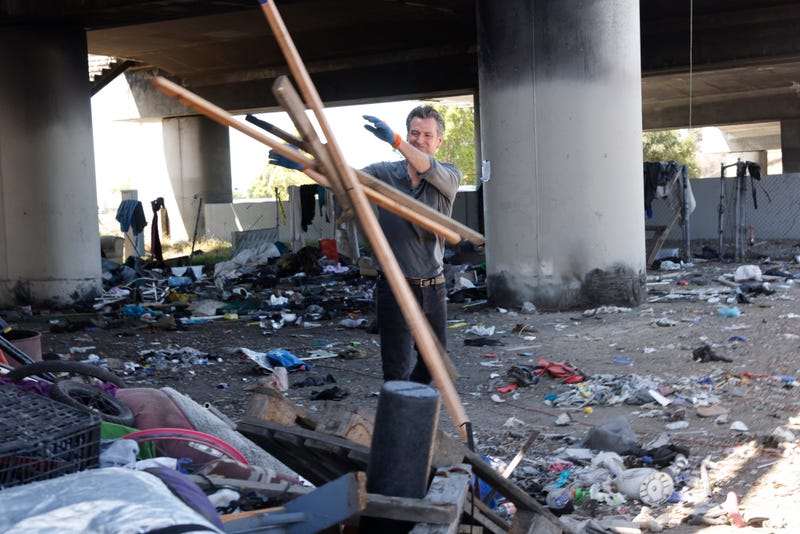 California Governor Gavin Newsom works with Caltrans in removing debris at a long-standing homeless encampment along Highway 80.
