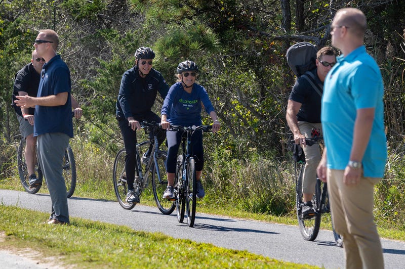 US President Joe Biden and First Lady Jill Biden (C) ride their bikes through Cape Henlopen State Park in Rehoboth Beach, Delaware, on September 19, 2021.