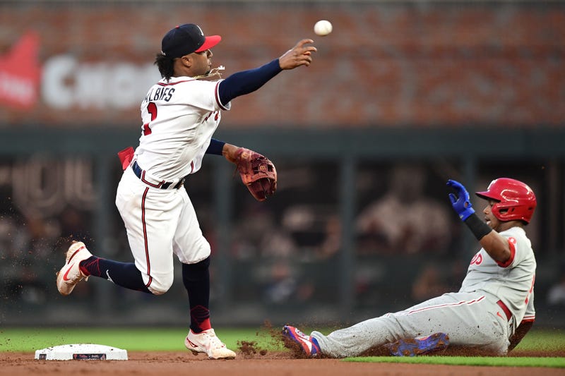 Ozzie Albies of the Atlanta Braves attempts to turn a double play against Jean Segura of the Philadelphia Phillies during the first inning at Truist Park on September 28, 2021 in Atlanta, Georgia.