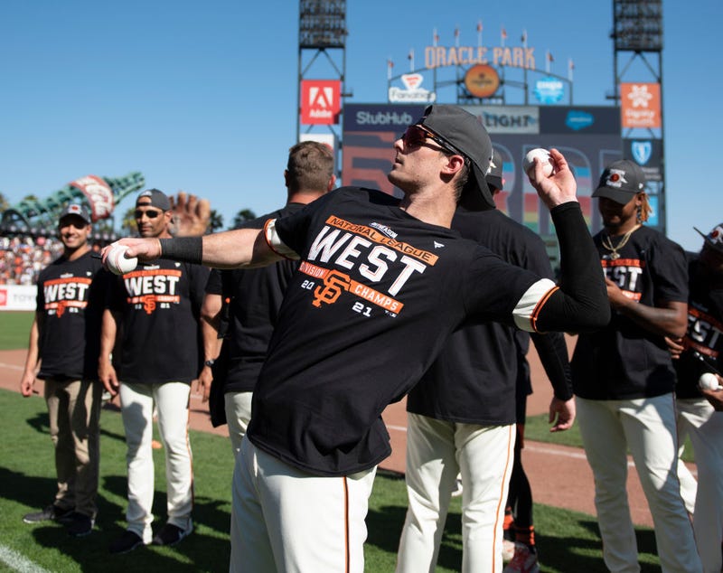 Mike Yastrzemski #5 of the San Francisco Giants signs a baseball and throws to the crowd after a game against the San Diego Padres at Oracle Park on October 03, 2021 in San Francisco, California.