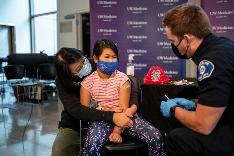 Elise Wong, 7, sits in the lap of her mother, Crystal Wong, after receiving a Pfizer-BioNtech Covid-19 vaccine from firefighter Luke Lindgren on November 3, 2021 in Shoreline, Washington.