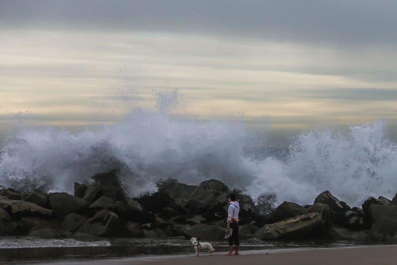 A man takes a picture of the big waves in the breakwater in Venice beach while he walks with his dog in Los Angeles. A tsunami advisory was in effect for the West Coast of the United States as well as Hawaii and Alaska after an undersea volcano erupted in the Pacific Ocean near Tonga. 