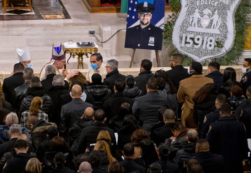 Archbishop of New York Timothy Dolan embraces a family member of slain NYPD officer Wilbert Mora during a funeral service at St. Patricks Cathedral on Feb. 2, 2022
