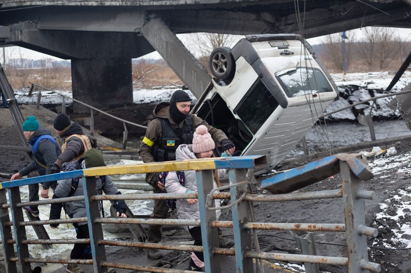 Ukrainian serviceman help a child cross the destroyed bridge on March 1, 2022 in Irpin, Ukraine