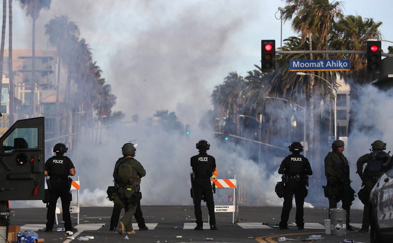 row of police in front of tear gas smoke on street