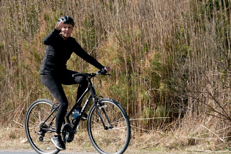 US First Lady Jill Biden waves while riding her bike through Cape Henlopen State Park in Rehoboth Beach, Delaware, on March 20, 2022. 