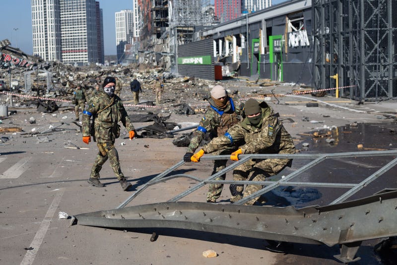 FILE - Ukrainian servicemen are seen at the explosion site as a result of a rocket strike into the shopping mall on March 21, 2022 in Kyiv, Ukraine. As Russia's advance on Kyiv has largely stalled, the Ukrainian capital has continued to be hit by missiles and shellfire. More than three million people have fled Ukraine since Russia launched its large-scale invasion of the country on Feb. 24.