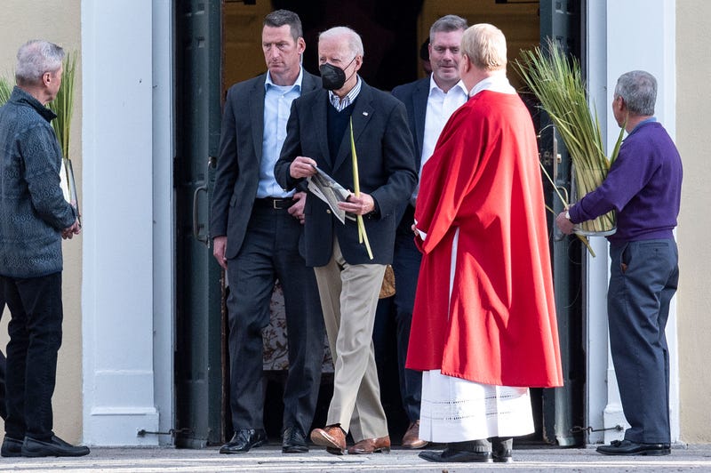 US President Joe Biden (C) holds a palm frond as he departs church service at St. Joseph on the Brandywine Catholic Church in Wilmington, Delaware, on April 9, 2022.