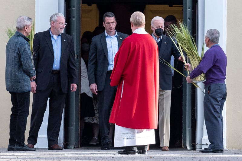 US President Joe Biden (2nd R) chooses a palm frond as he departs church service at St. Joseph on the Brandywine Catholic Church in Wilmington, Delaware, on April 9, 2022.