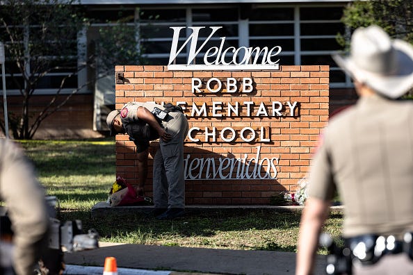 A Texas State Trooper receives flowers for the victims of a mass shooting yesterday at Robb Elementary School where 21 people were killed, including 19 children, on May 25, 2022 in Uvalde, Texas. The shooter, identified as 18-year-old Salvador Ramos, was reportedly killed by law enforcement. 