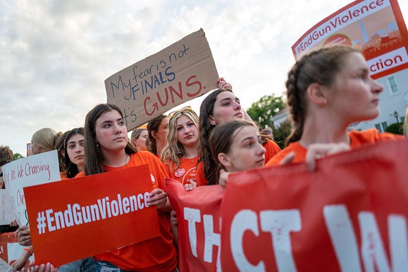 People hold up signs during a rally for National Gun Violence Awareness Day on June 03, 2022 in Newtown, Connecticut. Across the nation people are wearing orange and joining rallies as they demand change to America's gun laws.