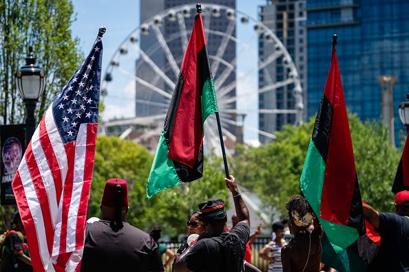 People raise American and Pan-African flags while marching in the Juneteenth Atlanta Black History parade on June 18, 2022 in Atlanta, United States.