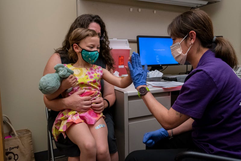 Nora Burlingame, 3, sits on the lap of her mother, Dina Burlingame, and gets a high five from nurse Luann Majeed after receiving her first dose of the Pfizer Covid-19 vaccination at UW Medical Center - Roosevelt on June 21, 2022 in Seattle, Washington.