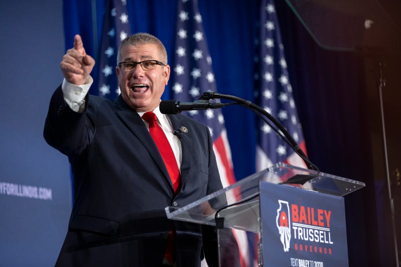 Darren Bailey stands at a podium smiling and pointing