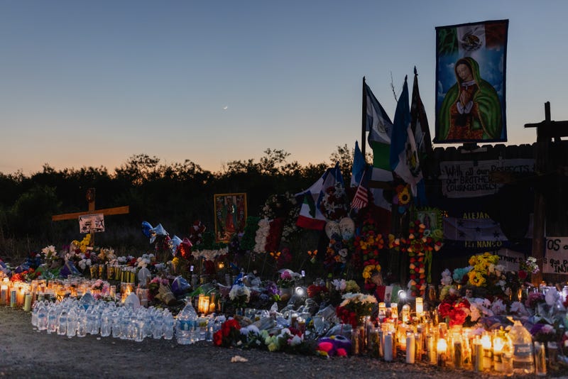 People gather at a makeshift memorial which has been erected at the site where 53 migrants died on June 30, 2022 in San Antonio, Texas.