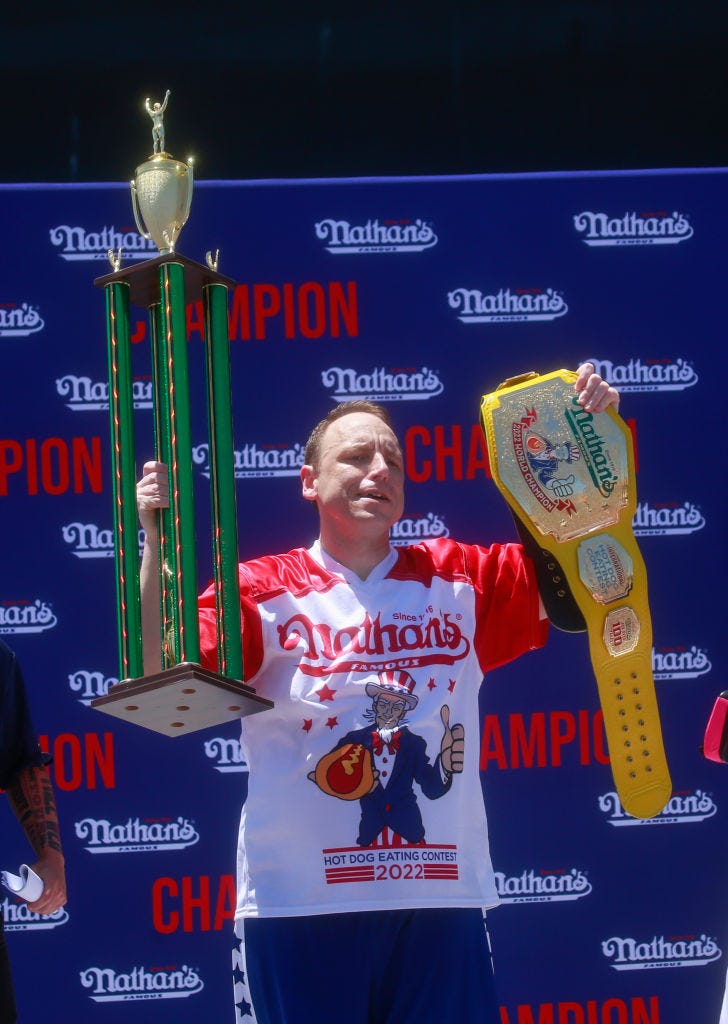 Joey Chestnut holds the trophy and belt after he won first place, eating 63 hot dogs in 10 minutes, during the 2022 Nathan's Famous Fourth of July International Hot Dog Eating Contest on July 4, 2022 at Coney Island in Brooklyn.