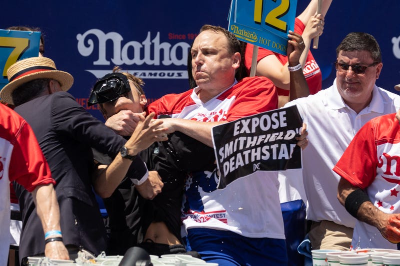 Joey Chestnut tackles a protester who interrupted the competition during the 2022 Nathan's Famous Fourth of July hot dog eating contest on Coney Island on July 4, 2022, in Coney Island