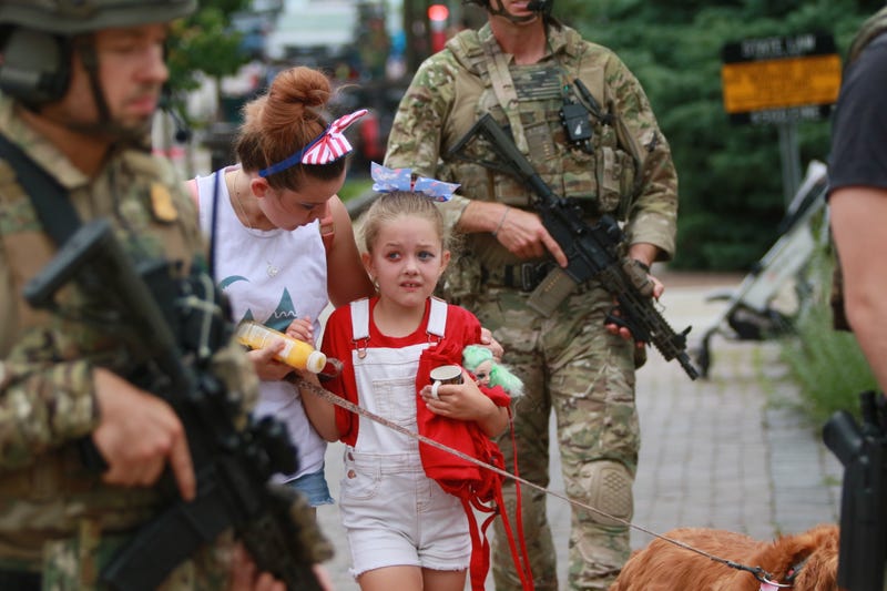A family is escorted by officers away from the 4th of July parade in Highland Park, Illinois.