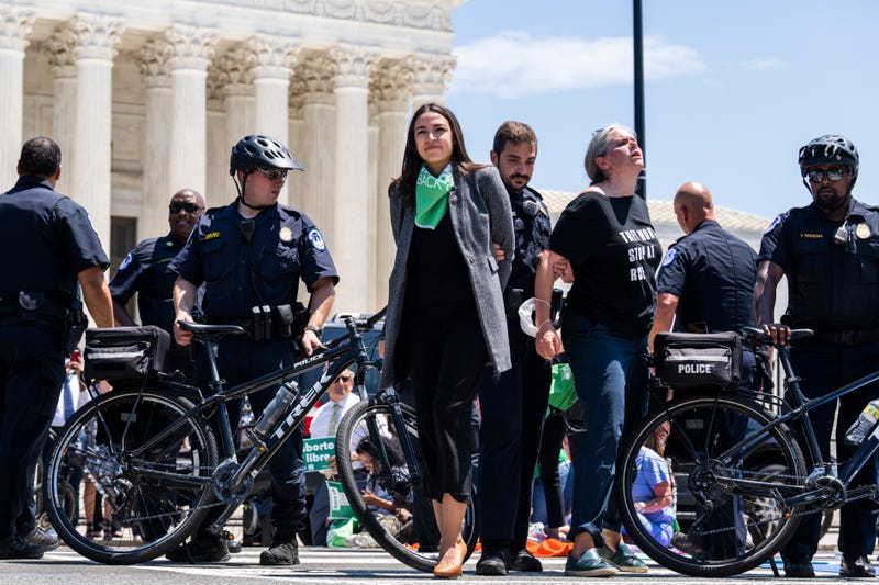 Rep. Alexandria Ocasio-Cortez, D-N.Y., center, is escorted away from a sit-in outside the Supreme Court with members of Congress to protest the decision to overturn Roe v. Wade on Tuesday, July 19, 2022