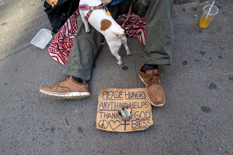 John, who is homeless, sits with his dog Daisy on a Manhattan street during a heat wave on July 22, 2022.