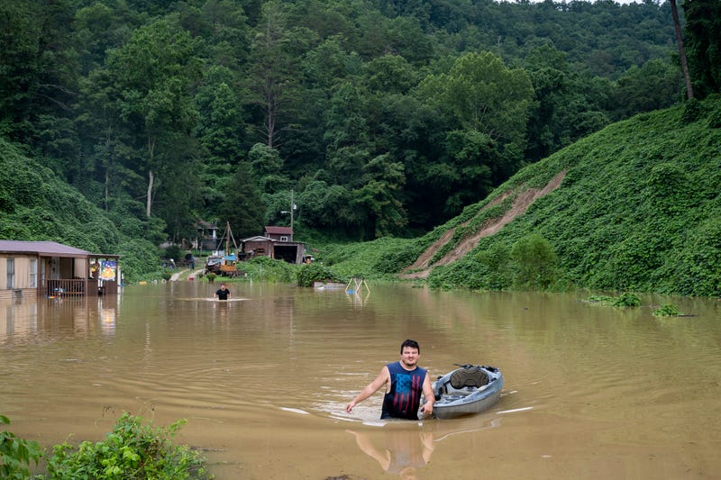 A man pulls a kayak through the water to deliver his father-in-law groceries in Jackson, KY.