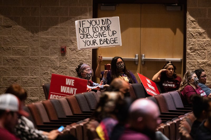 UVALDE, TX - AUGUST 24: Attendees hold signs as the Uvalde Consolidated Independent School District Board holds a special meeting to consider the firing of Police Chief Pete Arredondo on August 24, 2022 in Uvalde, Texas. Arredondo was fired over the police response to the May 24 massacre at Robb Elementary School, America’s deadliest school shooting since 2012.