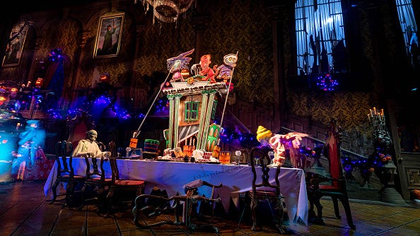 a gingerbread house is displayed on the ballroom table inside the Haunted Mansion at Disneyland Park