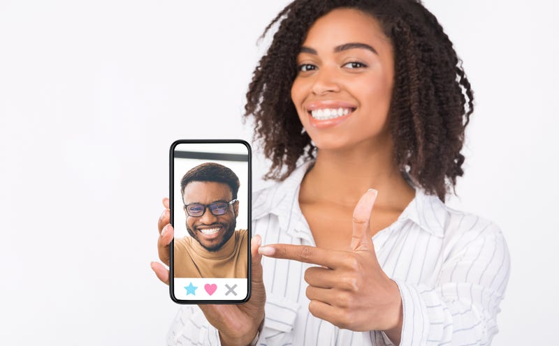 Online Dating App. Portrait of girl showing cell phone with male profile on the screen and pointing at it.