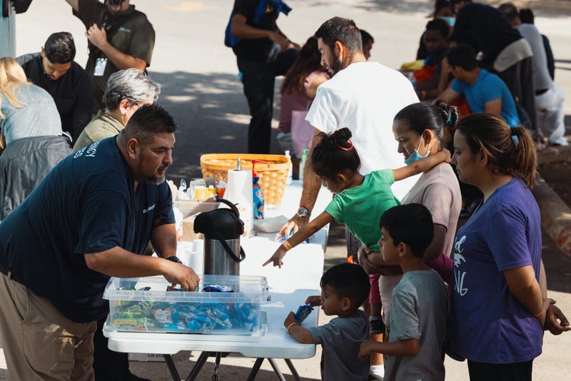 Groups of migrants receive food from the San Antonio Catholic Charities outside the Migrant Resource Center on Sept. 19, 2022, in San Antonio, Texas.